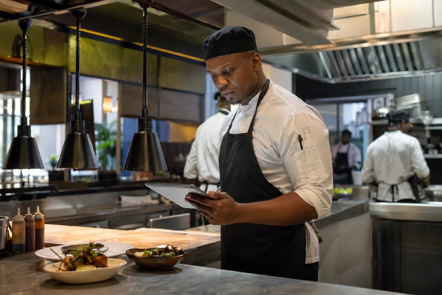 A chef checking incoming orders in a working restaurant kitchen