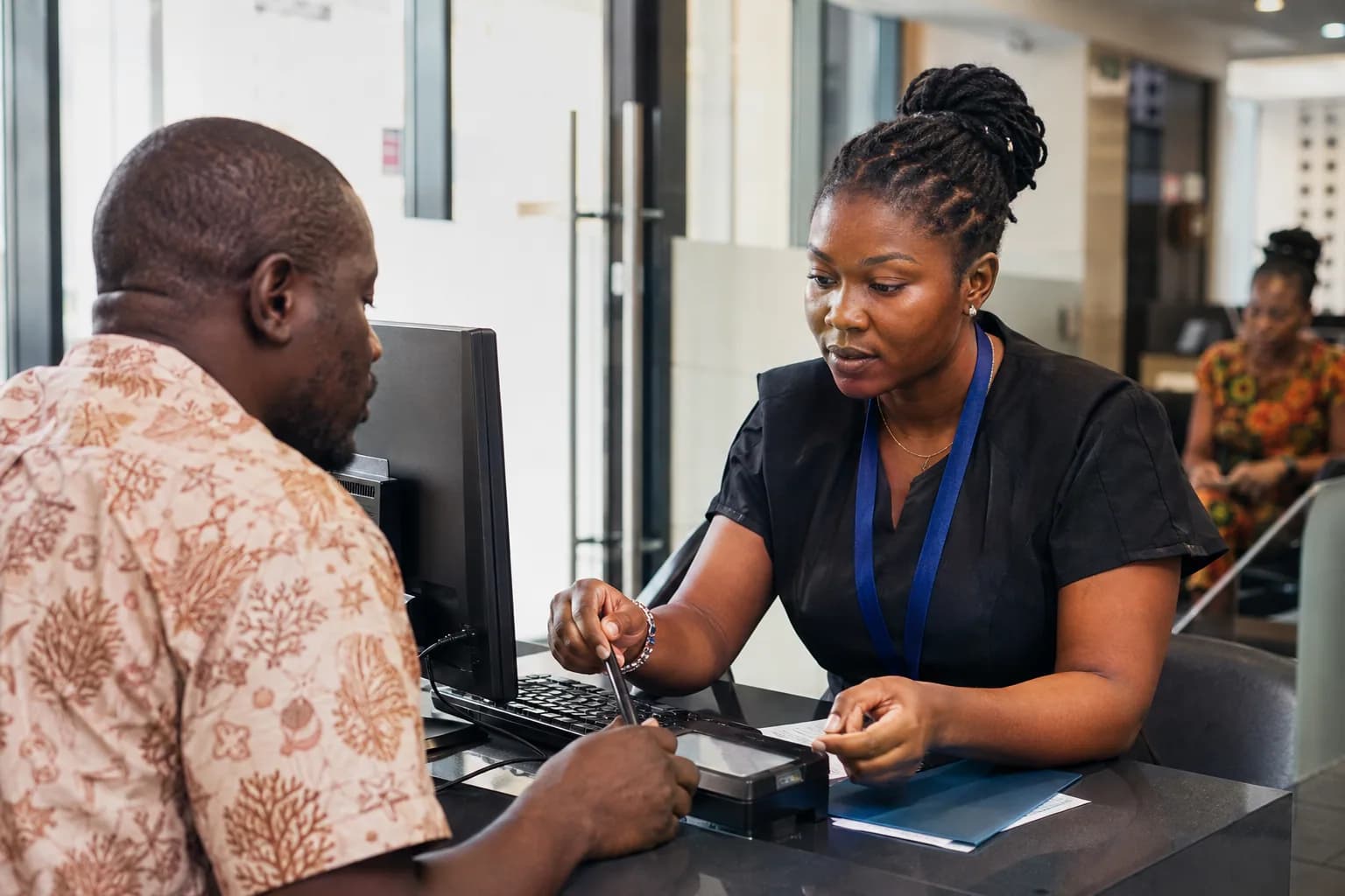 A public-service officer helping a citizen at a digital service desk