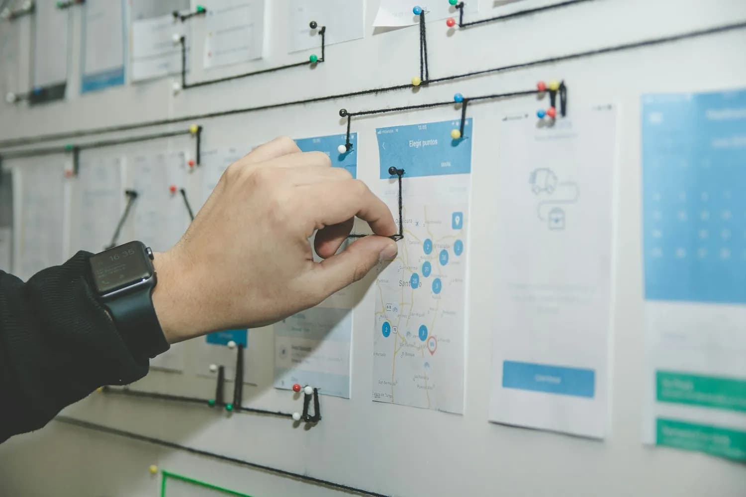 A product designer pinning interface wireframes on a planning wall